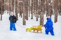 Two small children with sleds in the forest. Family walk in the woods