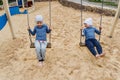 Two small children swing on the swing outdoors