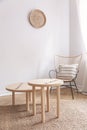 Two small coffee tables and wicker chair with pillow on it in natural beige living room