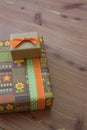 Two small gift boxes in green orange and brown with ribbons, retro style, neutral wood background Royalty Free Stock Photo