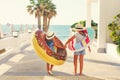 Two small girls with inflatable toys on the beach