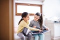 Two small girls sisters indoors at home, reading books. Royalty Free Stock Photo