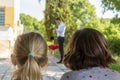 Two small girls are watching a performance of a magician through an outdoor birthday party