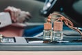 Two small glass bottles with car perfume on car panel. Female driver on blurry background