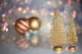 Two small Golden Christmas tree on the glass surface with defocused background with bokeh lights and a Christmas balls Royalty Free Stock Photo