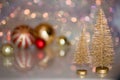 Two small Golden Christmas tree on the glass surface with defocused background with bokeh lights and a Christmas balls Royalty Free Stock Photo