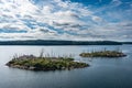 Two small islands with dead trees. Panoramic view of beautiful evergreens small islands and rocky coast of Scandinavia on sunny Royalty Free Stock Photo