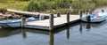 Two small motor boats tied to a dock in beach grass Royalty Free Stock Photo