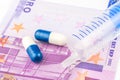 Two small pills and one injection are laying on 500 euro banknote