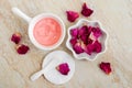 Two small porcelain bowls with rose jelly face mask and dry rose petals. Natural skin care, homemade spa, beauty treatment recipe. Royalty Free Stock Photo