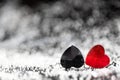 Two small red and black plastic hearts lying next to each other with beautiful silver bokeh effects and a copy space for text. Royalty Free Stock Photo