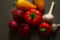 two small red and two yellow sweet peppers, two garlic bulbs, three dark red onion Royalty Free Stock Photo