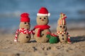 Two small sandy snowmen and santa at tropical beach.