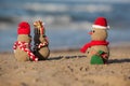 Two small sandy snowmen and santa at tropical beach.