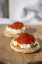 Two small starters blinis with sour cream and salted salmon red caviar served on mango tree wooden board Royalty Free Stock Photo