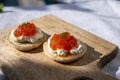 Two small starters blinis with sour cream and salted salmon red caviar served on mango tree wooden board Royalty Free Stock Photo