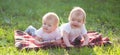 Two small twin children play on blanket on the green