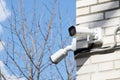 Two small white CCTV cameras on the corner of the facade of a multi-storey brick building against a blue sky Royalty Free Stock Photo