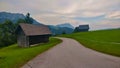 Two small wooden barns on each side of the road in the alpine area