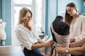 Two smart-looking pretty women wearing white shirts are looking at the tailor`s dummy. Fashion, tailor`s workshop. Royalty Free Stock Photo