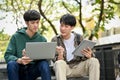 Two smart young Asian male college students using laptop, discussing and working together Royalty Free Stock Photo