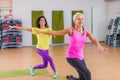 Two smiling athletic women doing aerobic dancing exercises holding their arms sideward indoors in fitness center. Royalty Free Stock Photo