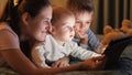 Two smiling brothers in pajamas playing on tablet computer with mother before going to sleep. Family having time together, Royalty Free Stock Photo