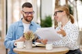 Two smiling business colleagues young man and woman working together on project at outdoor cafe Royalty Free Stock Photo