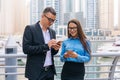 Two smiling business man and woman with mobile phone in hands are having pleasant conversation on skyscrapers background Royalty Free Stock Photo