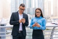 Two smiling business man and woman with mobile phone in hands are having pleasant conversation on skyscrapers background Royalty Free Stock Photo
