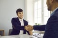 Two smiling business people shaking hands after signing the contract sitting in office. Royalty Free Stock Photo