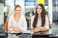 Two smiling businesswomen sitting in the office and looking at camera Royalty Free Stock Photo