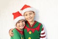 two smiling cute boys in Santa hats and elf costumes hug each other on a light background Royalty Free Stock Photo