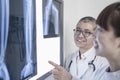 Two smiling doctors looking at x-rays of human bones, pointing