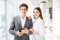 Two smiling elegant business people man in formal suit and woman in jacket and dress looking at something on digital tablet in off Royalty Free Stock Photo