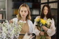 Two smiling female florists working behind counter in modern loft interior of floral shop. Royalty Free Stock Photo