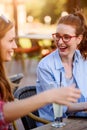 Two smiling female friends talking, drinking coffee outdoors in the city Royalty Free Stock Photo