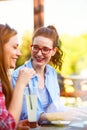 Two smiling female friends talking, drinking coffee outdoors in the city Royalty Free Stock Photo