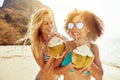 Two smiling friends walking along a beach drinking from coconuts Royalty Free Stock Photo