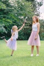 Two smiling funny Caucasian girls sisters wearing pink tutu tulle skirts in park forest meadow at sunset. Friends having fun Royalty Free Stock Photo