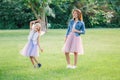 Two smiling funny Caucasian girls sisters wearing pink tutu tulle skirts in park forest meadow at sunset. Friends having fun Royalty Free Stock Photo