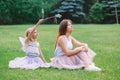 Two smiling funny Caucasian girls sisters wearing pink tutu tulle skirts in park forest meadow at sunset. Friends having fun Royalty Free Stock Photo