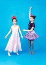 Two smiling funny girls in party costumes posing on blue background