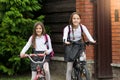 Two smiling girls leaving to school on bicycles