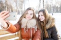 Two smiling girls make selfie in winter park Royalty Free Stock Photo