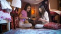 Two smiling girls in pajamas reading big book in selfmade tent