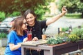 Two smiling girls taking selfie on smartphone, sitting at cafeteria outdoors, have a break together in summer day. Royalty Free Stock Photo