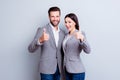 Two smiling happy businesspeople in formalwear showing thumbs-up on gray background Royalty Free Stock Photo