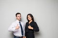 Two smiling happy businesspeople in formalwear showing thumbs-up on gray Royalty Free Stock Photo