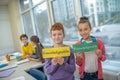 Two smiling kids holding the word knowledgeable